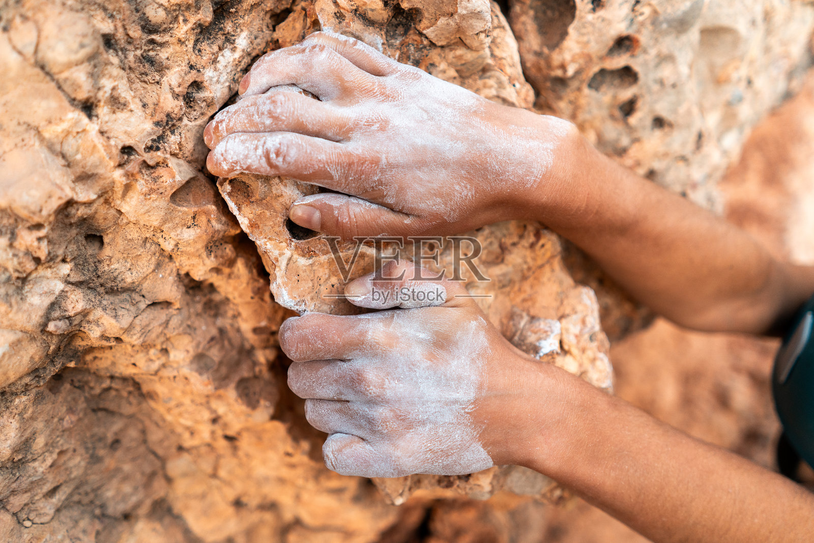 无畏地攀岩，使用白色镁粉，手扶着岩石边缘，获得解放照片摄影图片