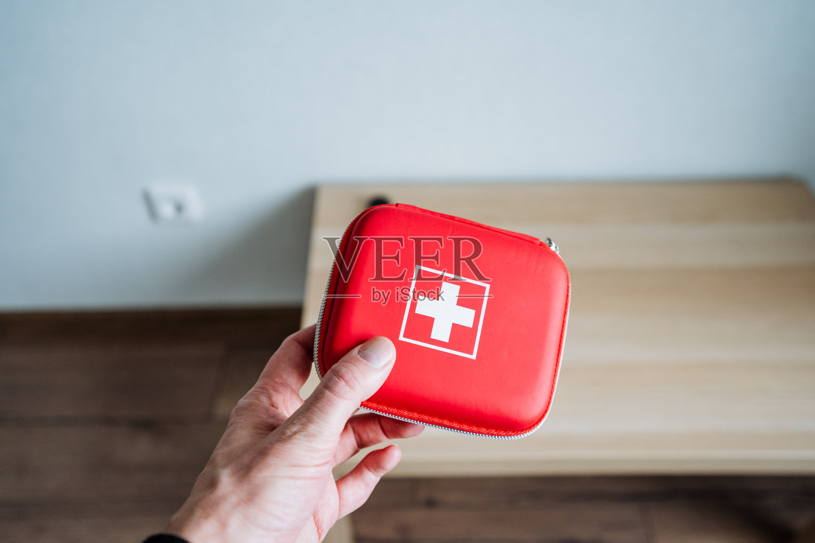 一个人自信地拿着一个鲜红色的急救箱，箱体上醒目地标有白十字徽章，象征着医疗援助和关怀。照片摄影图片
