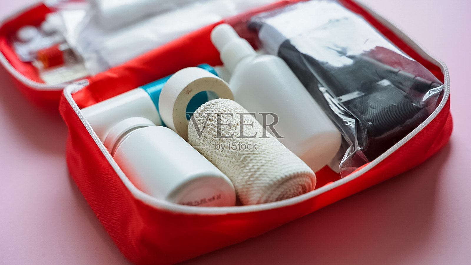 一个鲜红色的急救箱，里面装有各种药瓶、喷雾瓶和成套的绷带，确保您拥有应对任何紧急情况所需的所有用品照片摄影图片