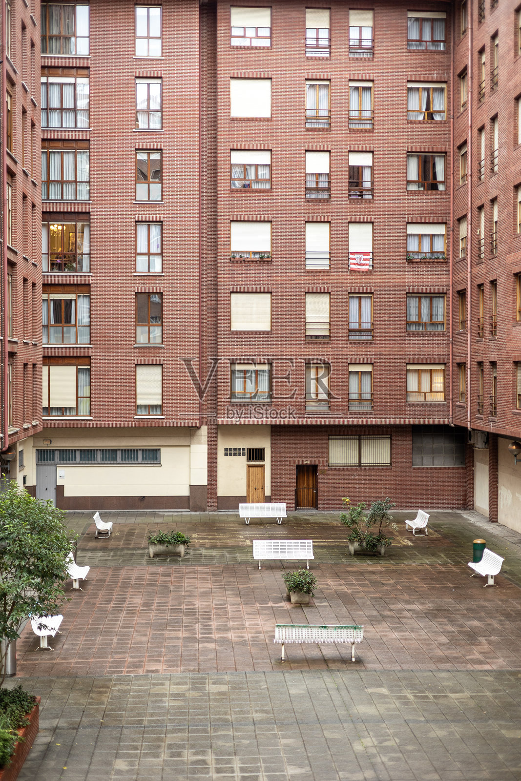 位于毕尔巴鄂 Uribarri 或 Matiko 街区的红色砖砌大型公寓住宅的宁静内部庭院。照片摄影图片