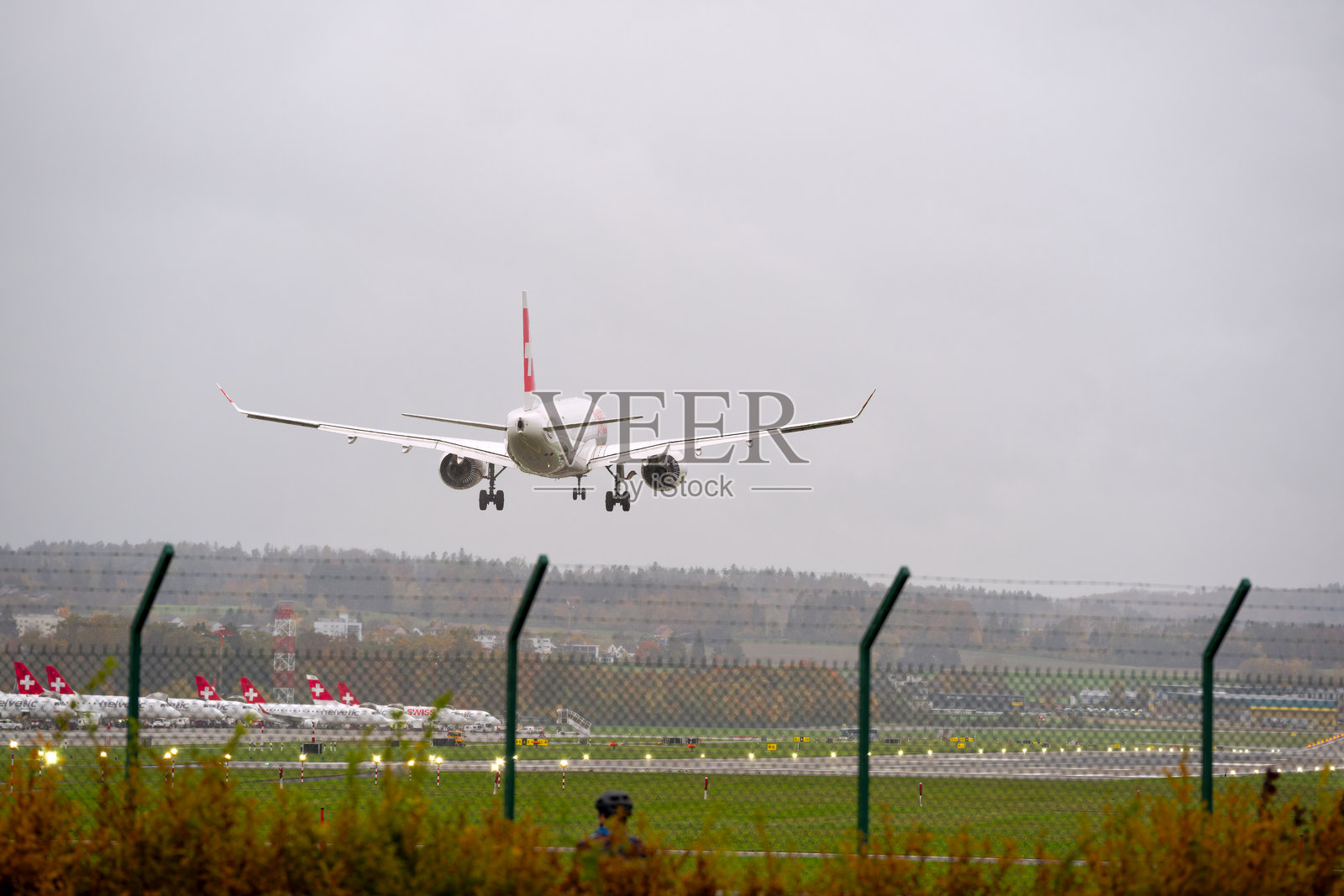 一架空中客车A220-300飞机（注册号HB-JCI）在秋天一个阴雨大风的日子里，降落在瑞士苏黎世机场。照片摄影图片