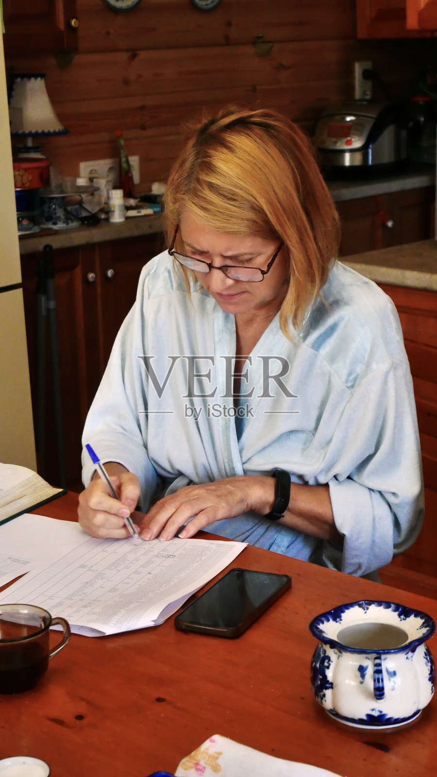 专注的女性在厨房餐桌上处理文书工作照片摄影图片