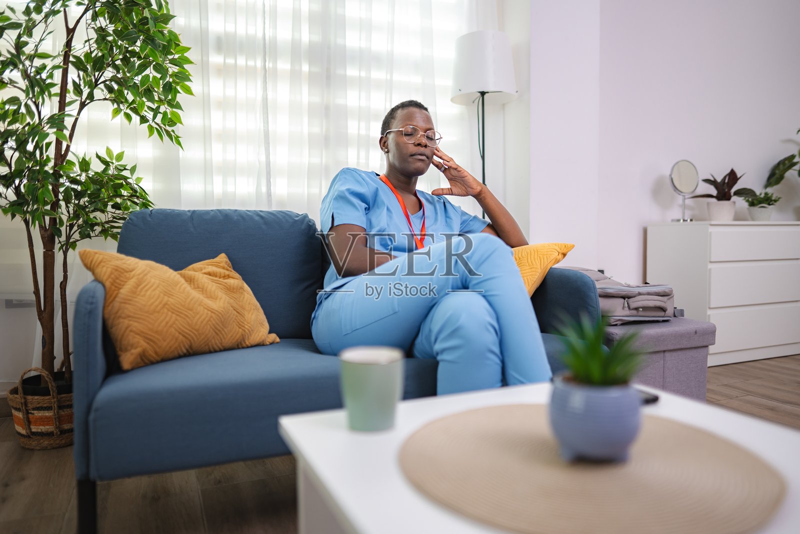 下班后疲惫的护士坐在家里的沙发上照片摄影图片