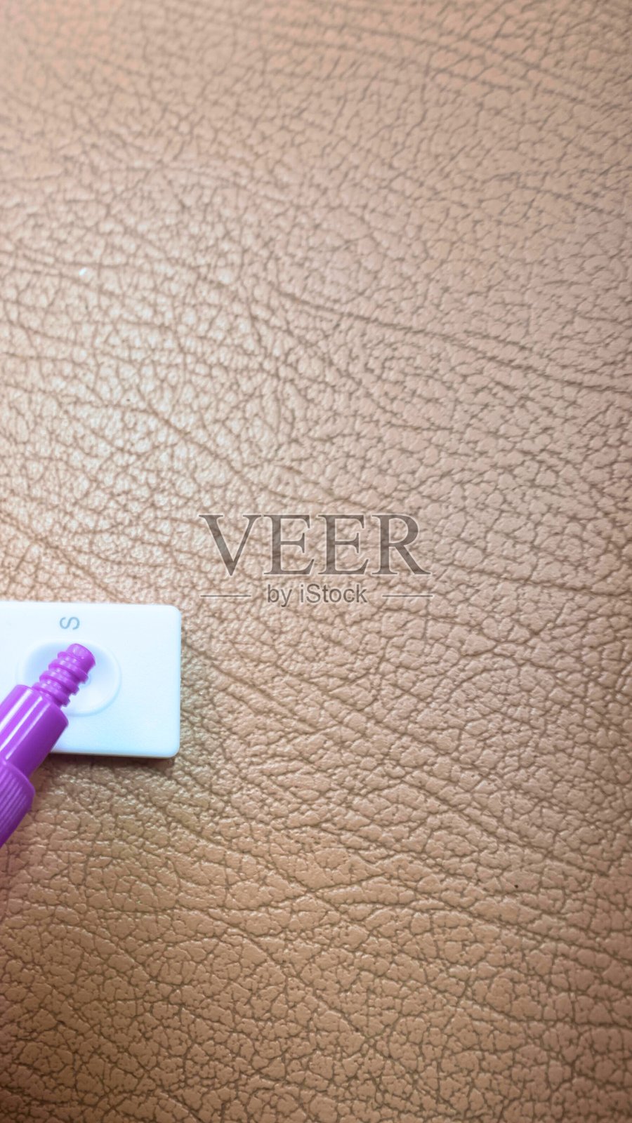 特写：一只手将白色贴纸贴在有纹理的棕色表面上照片摄影图片