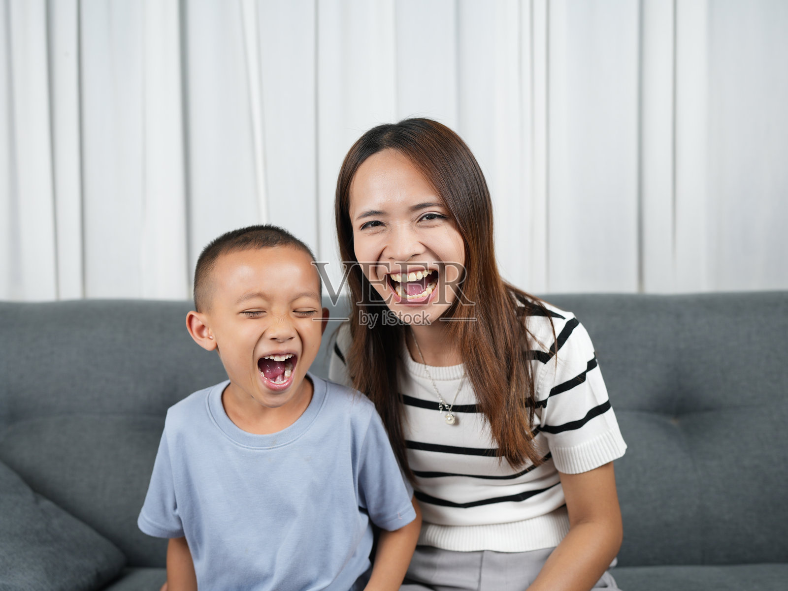 快乐的母子俩在沙发上开怀大笑，展现了充满爱意的温馨连接时刻。他们脸上洋溢着温暖和幸福的笑容，构成了一幅令人动容的画面。照片摄影图片