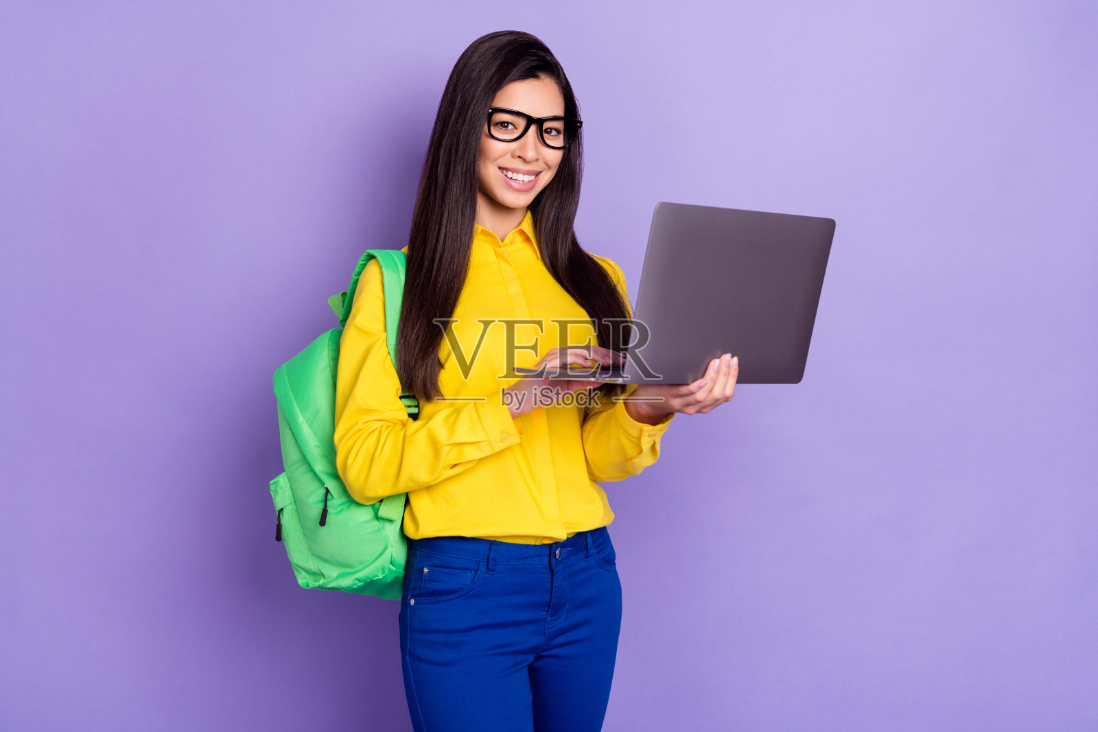 正面照，一位积极迷人的年轻女子，手持笔记本电脑，学生，教育，孤立在紫色背景上照片摄影图片