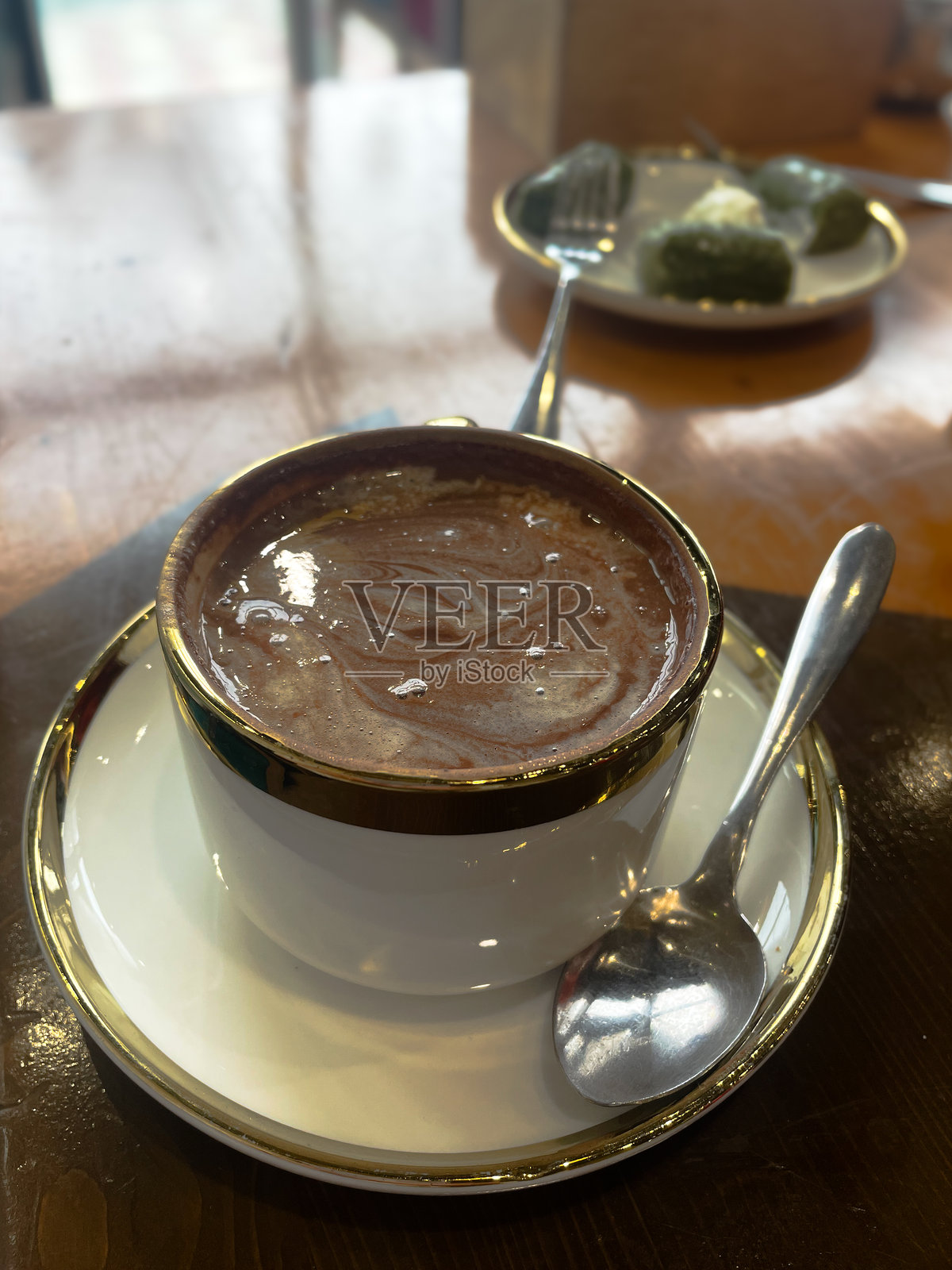 木桌上的白色瓷杯热巧克力，杯口有金色镶边照片摄影图片