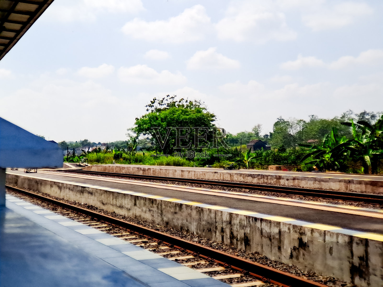 乡村火车站台宁静的一天，有绿植和多云的蓝天景色。照片摄影图片