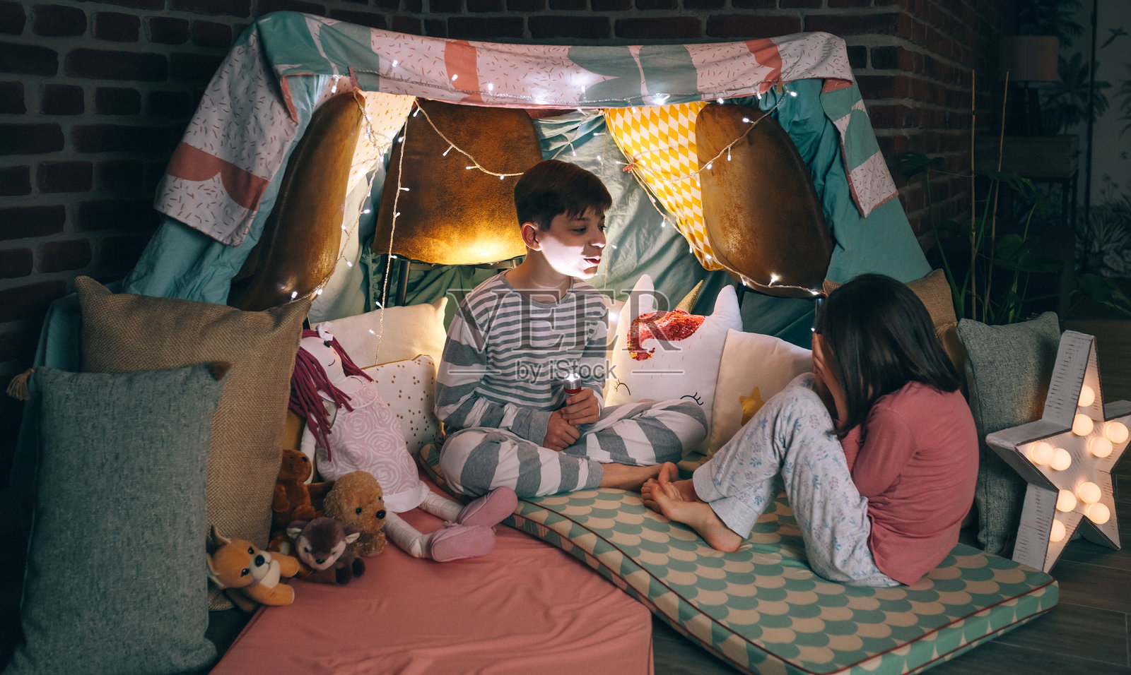 孩子用灯笼照亮做出恐怖手势，而受惊的小女孩用手捂住脸照片摄影图片