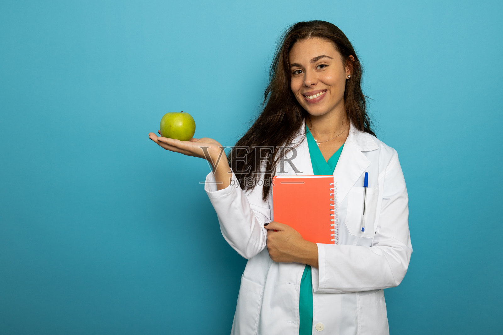 年轻女医生身穿实验服手拿青苹果的肖像照照片摄影图片
