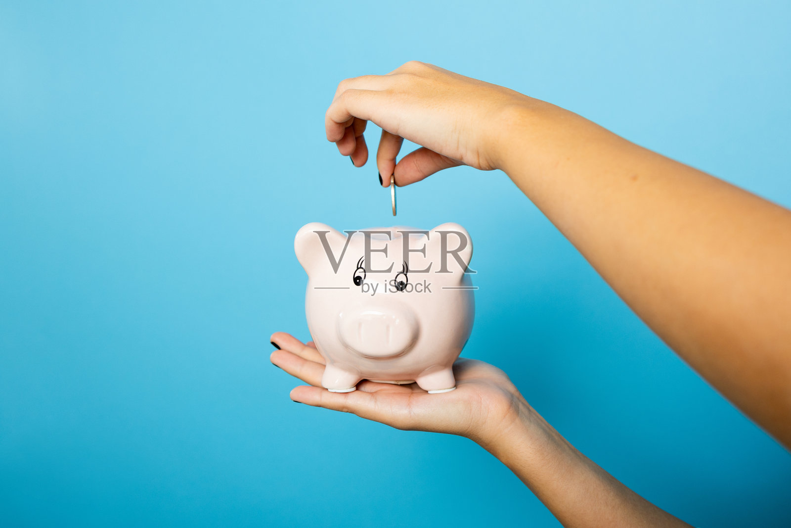 年轻女人拿着小猪存钱罐，象征着金融储蓄照片摄影图片