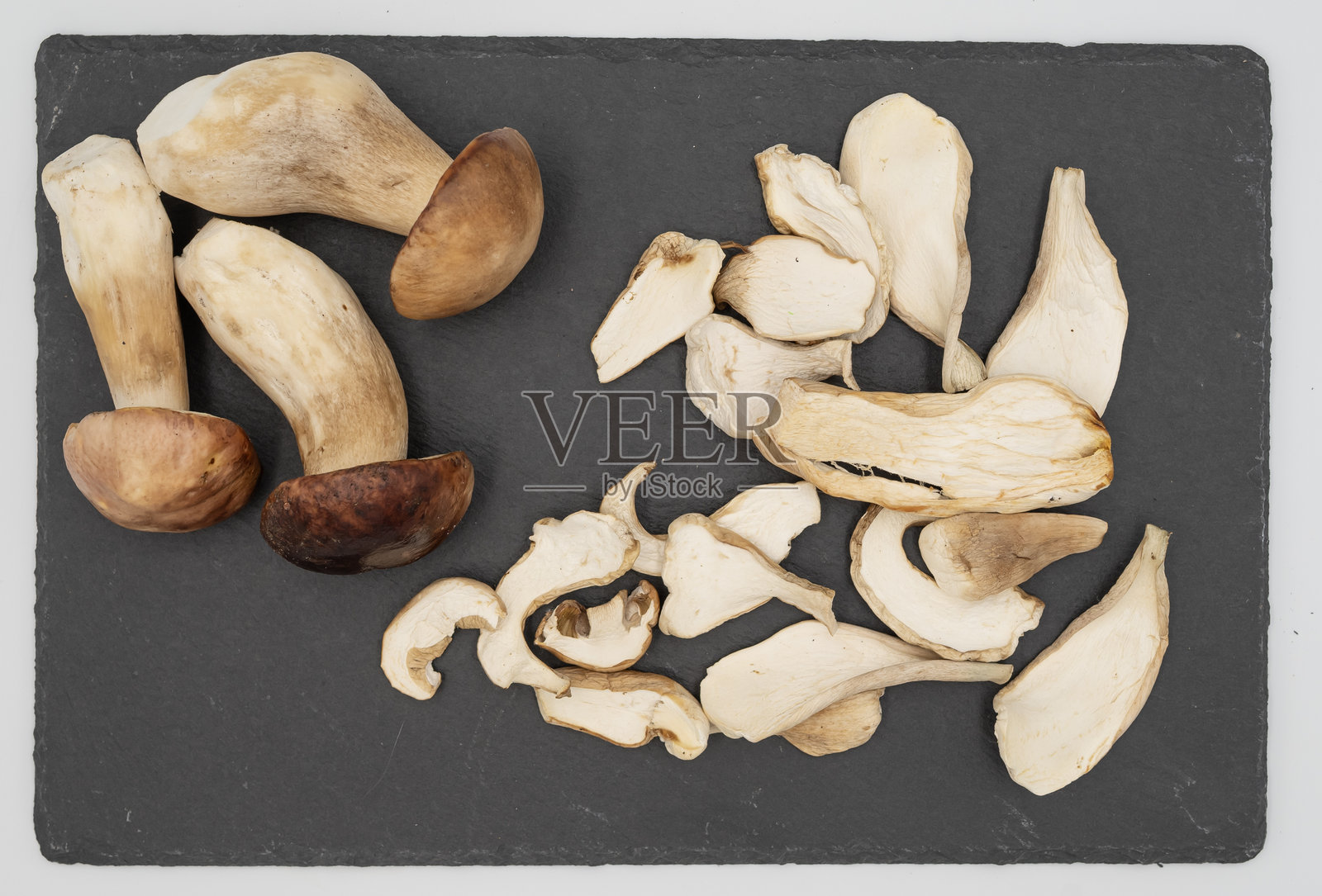 新鲜的牛肝菌配干切片放在石板上照片摄影图片
