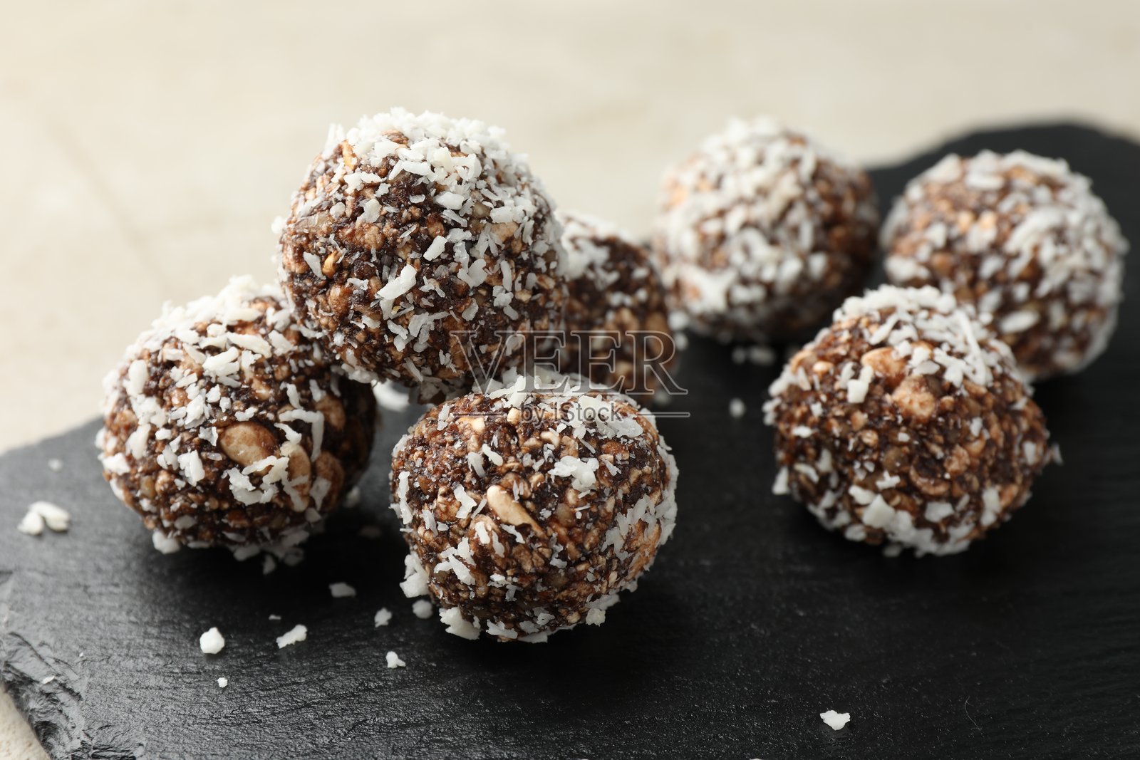 浅色桌上的美味巧克力糖果，配有坚果和椰子片，特写照片摄影图片