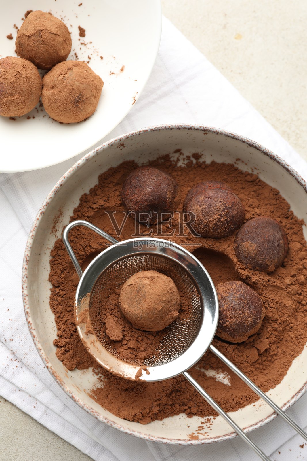 在浅色桌面上用可可粉制作美味的巧克力糖果，俯视角度照片摄影图片