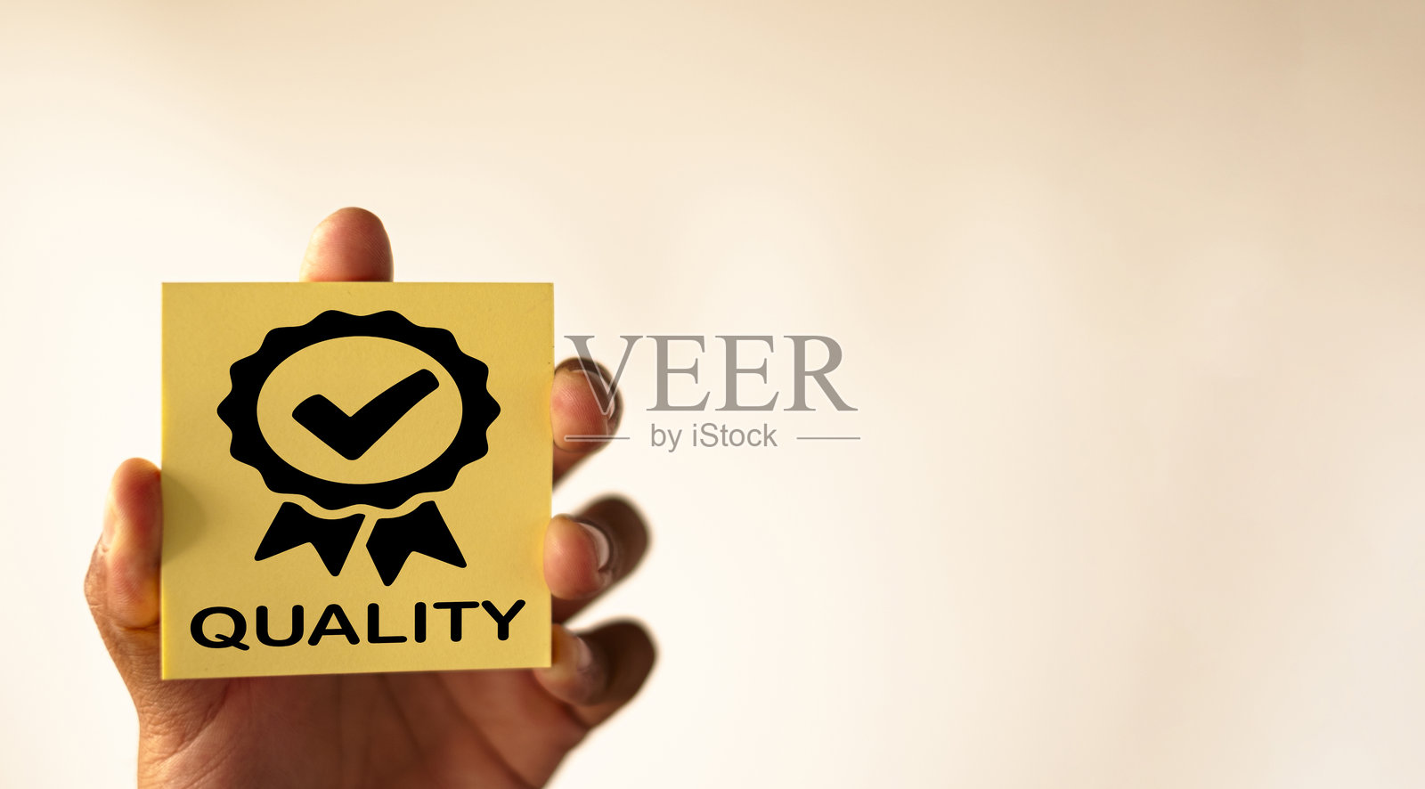 质量保证概念：一只手拿着带有认证质量图标的便签。照片摄影图片