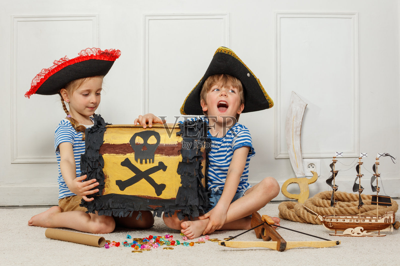 穿着海盗服装的孩子们玩着宝箱和玩具船照片摄影图片