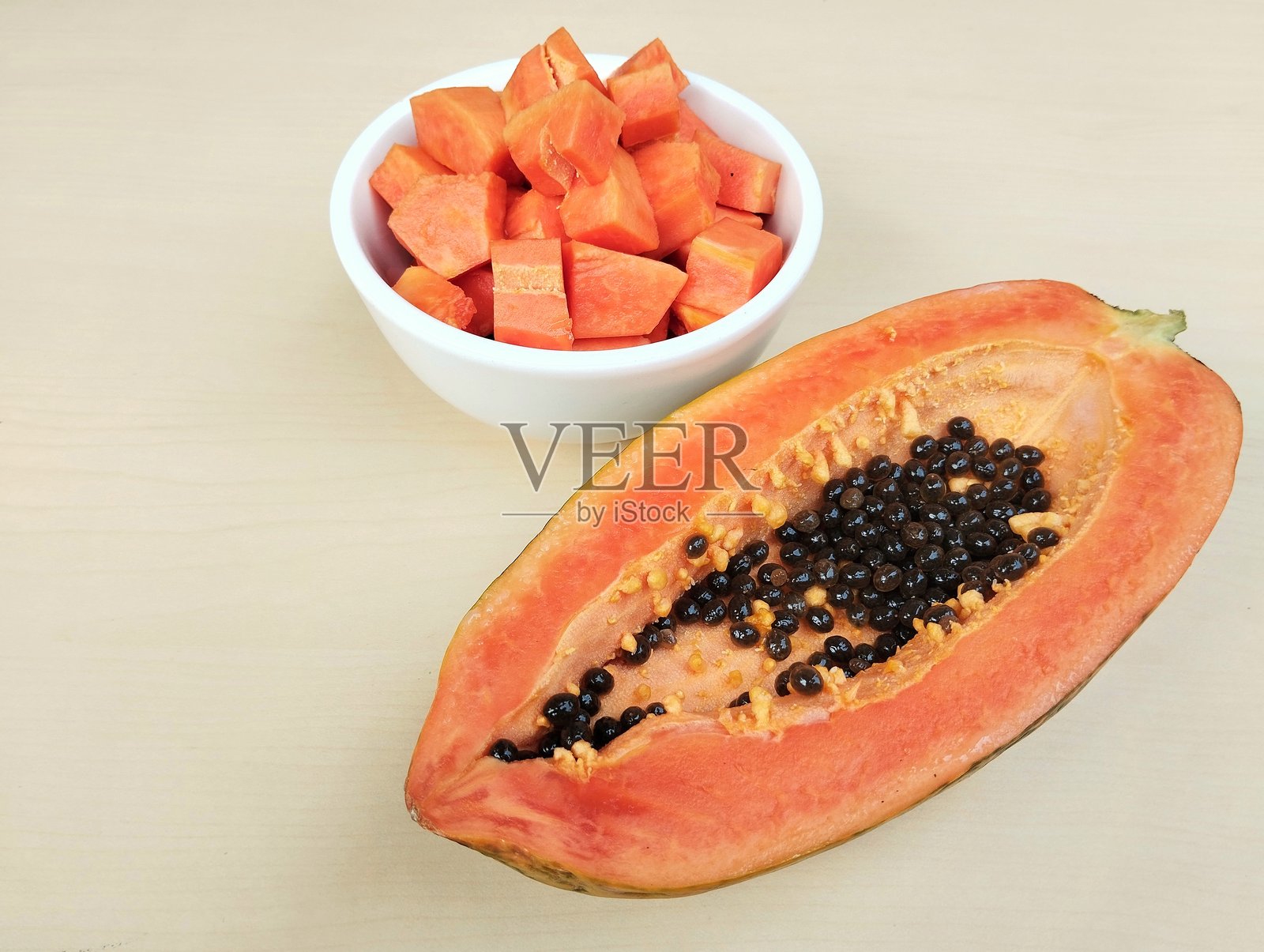 碗里的木瓜切片和木瓜半个放在木桌上照片摄影图片
