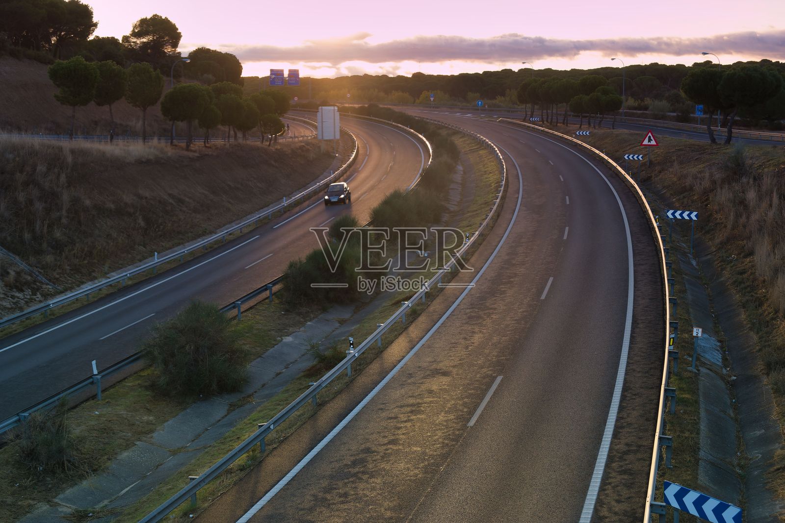 夕阳映照下的蜿蜒公路，傍晚时分，一辆孤独的汽车在宁静的道路上行驶照片摄影图片