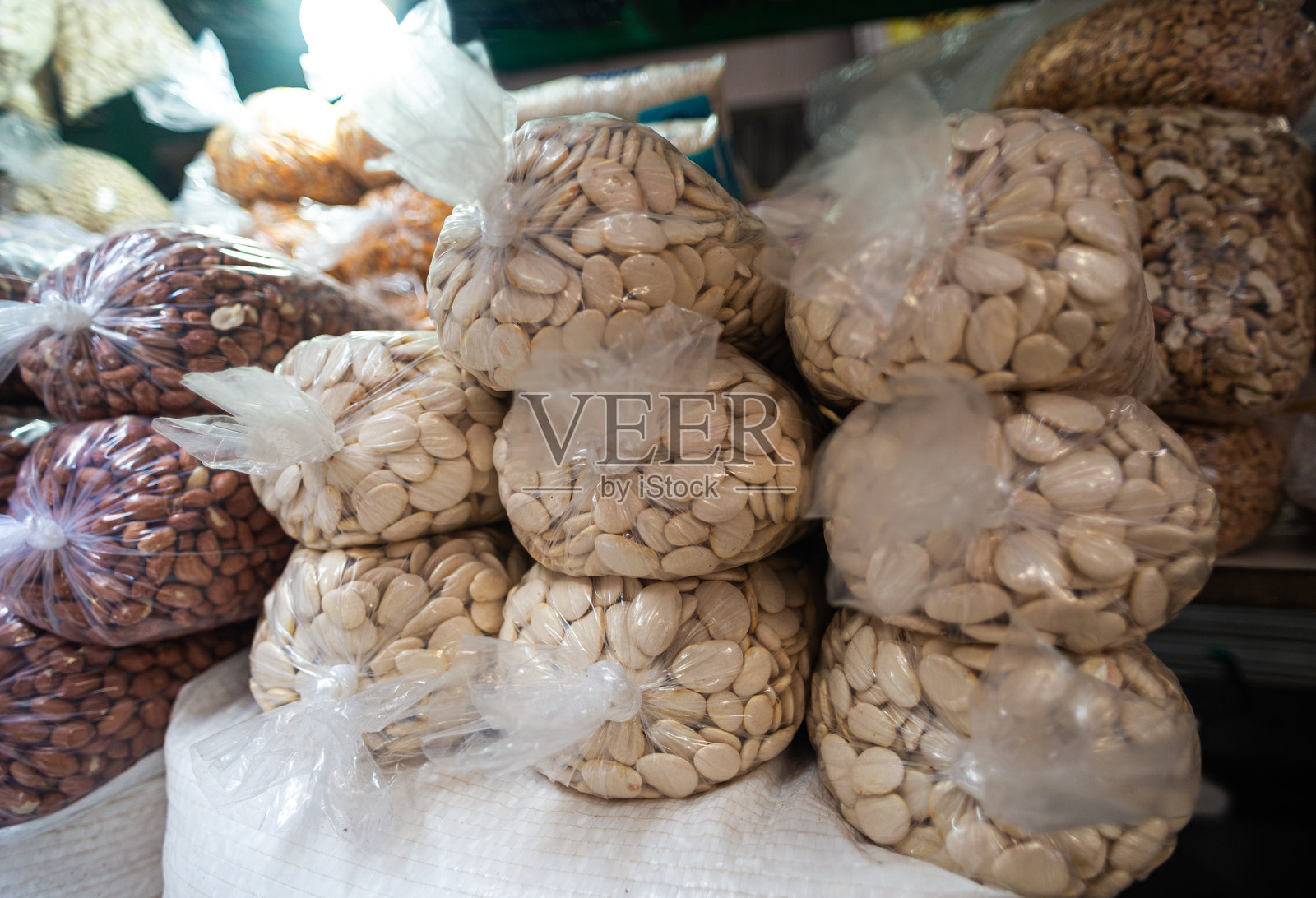 市场摊位上摆放着各种装在透明袋子里的坚果，包括杏仁和花生。照片摄影图片