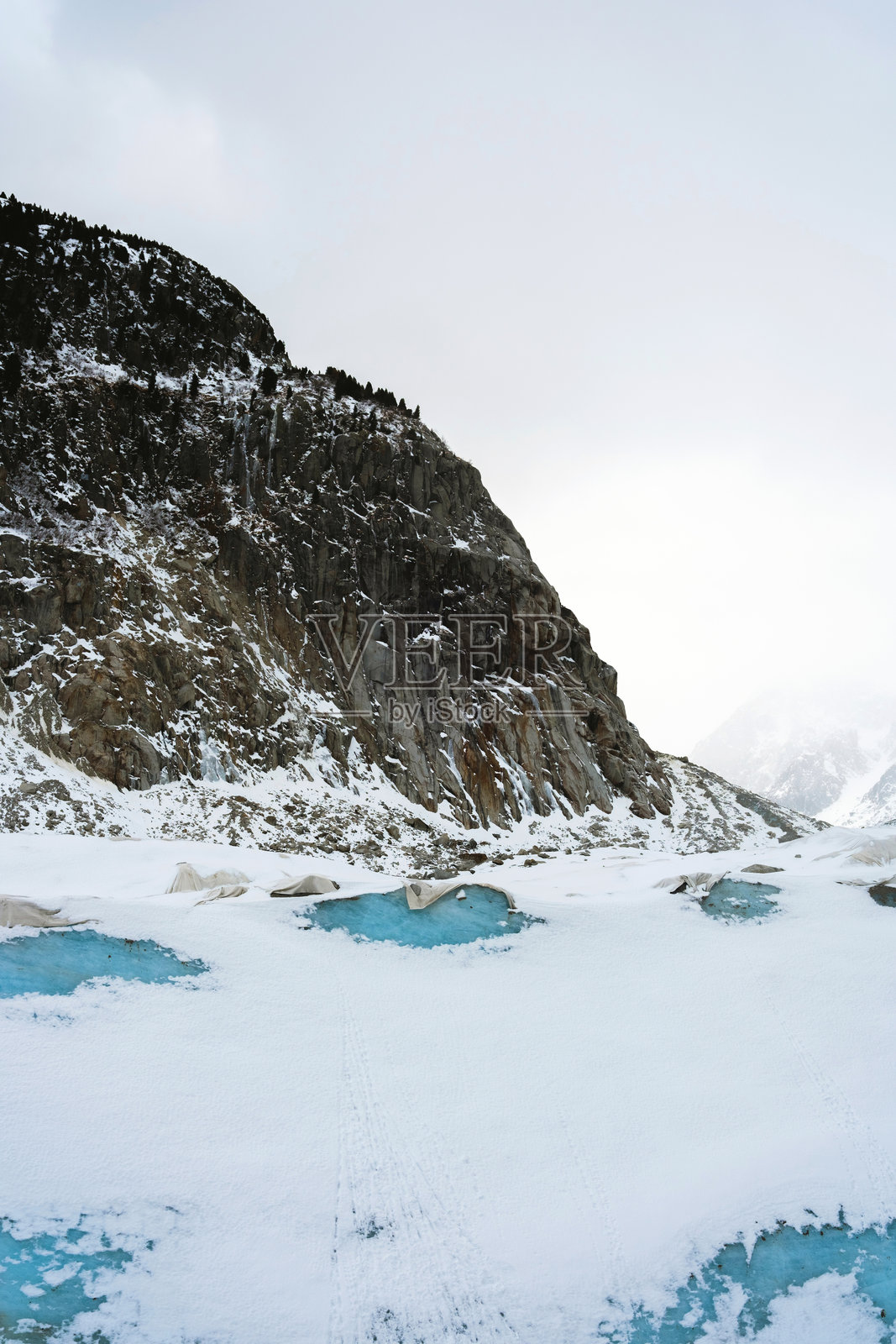 冬季风景中，白雪皑皑的阿尔卑斯山坡，点缀着明亮的蓝色冰池照片摄影图片
