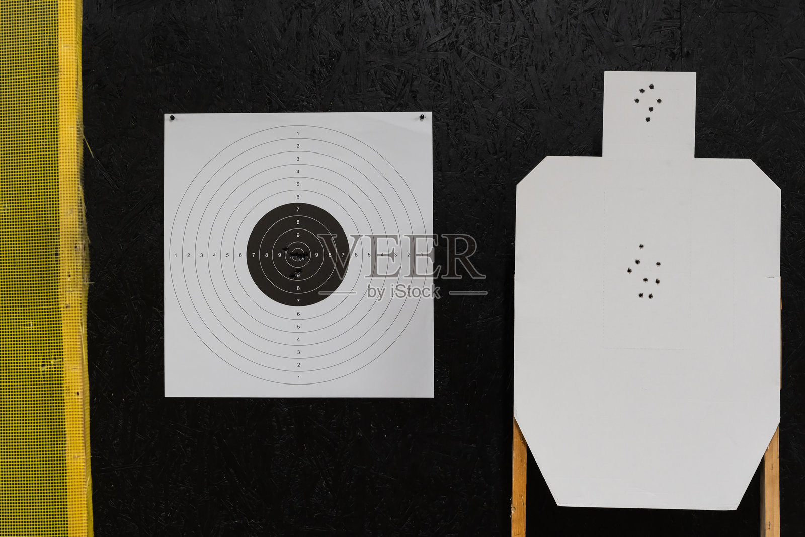 靶场上的两个射击靶，一个中心有命中的靶心，一个有头部和躯干精确命中标记的剪影。照片摄影图片