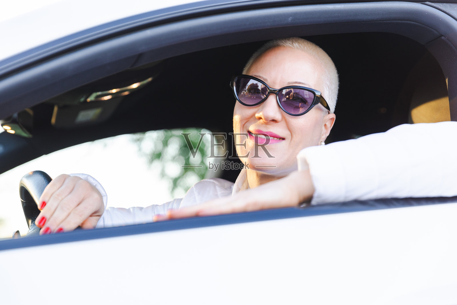 戴着太阳镜、微笑着、时尚又轻松地开车的自信女性照片摄影图片
