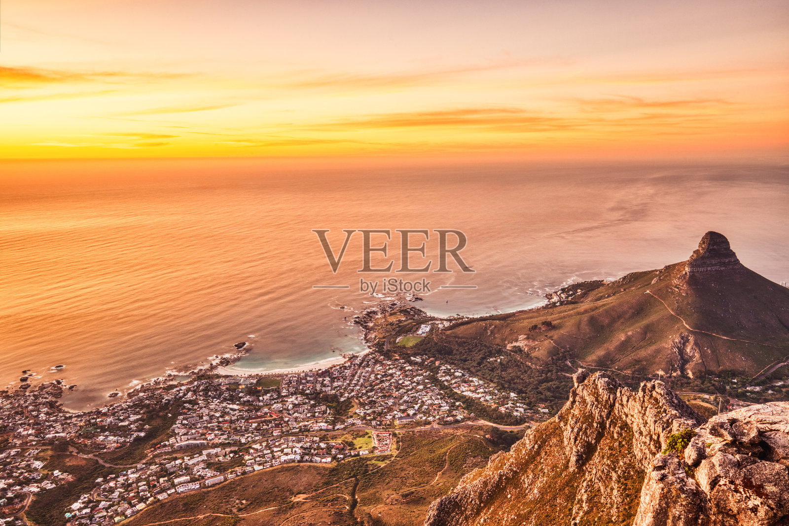 从桌山俯瞰开普敦日落，背景为坎普斯湾、狮头山和十二使徒岩照片摄影图片