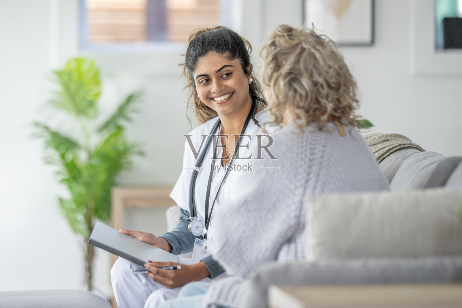 身着制服的亚裔护士在温馨的家中为老年患者听诊照片摄影图片