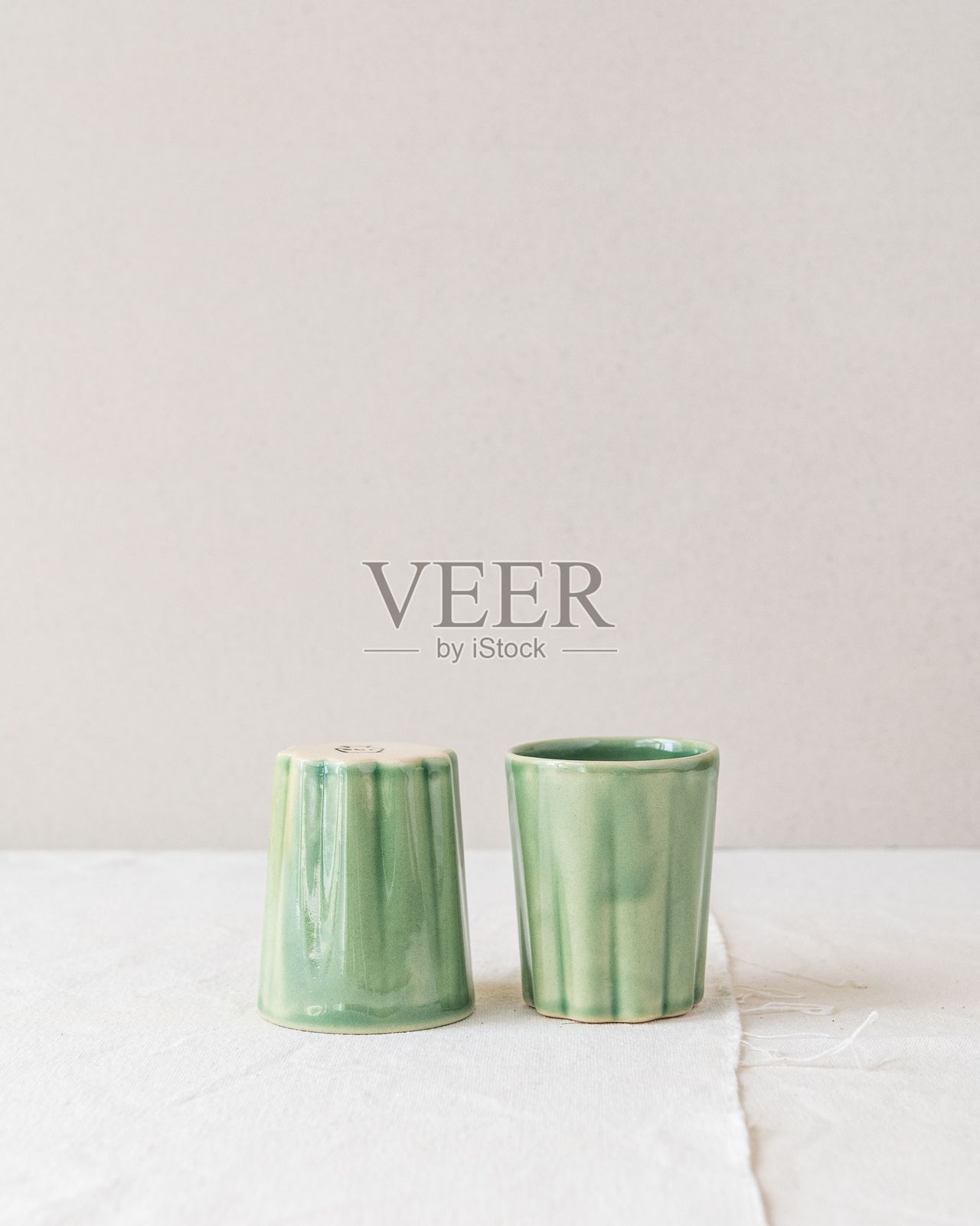 浅色表面上的绿色陶瓷杯照片摄影图片