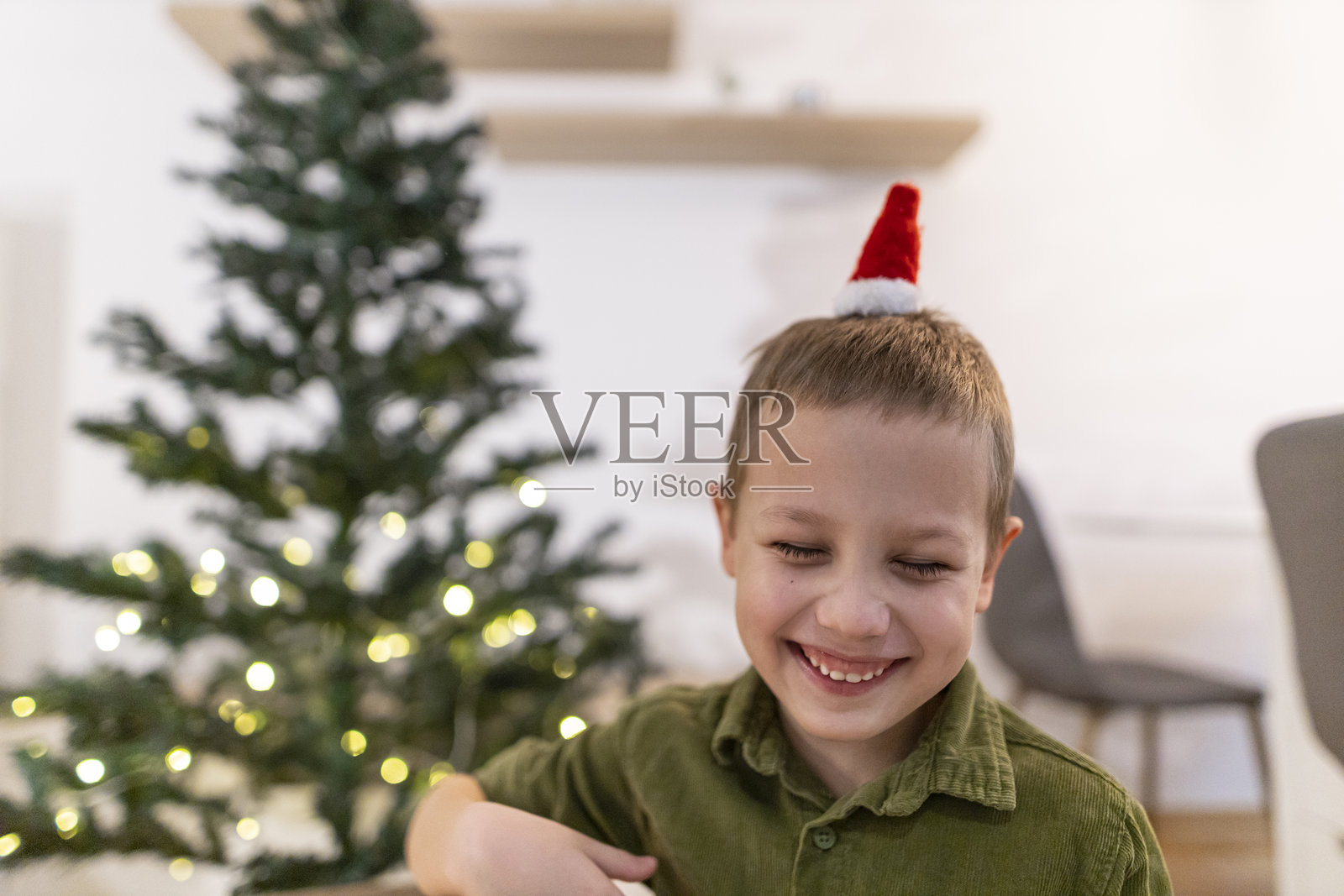 小男孩在圣诞树旁准备节日装饰品。照片摄影图片