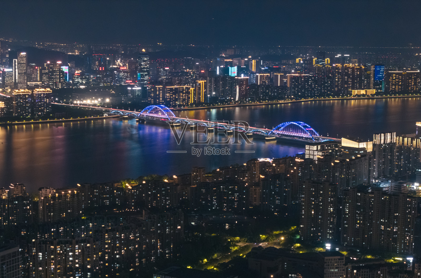 夜幕下的杭州城市灯火辉煌，一座现代化的桥梁横跨宽阔的河流照片摄影图片