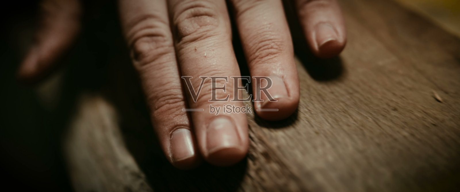 特写：一只人手轻轻放在有纹理的木质表面上照片摄影图片