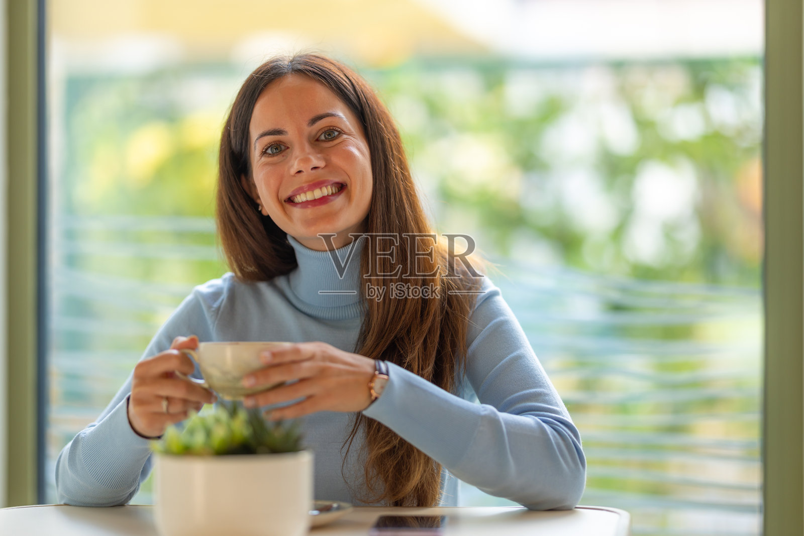 一位女士手捧咖啡杯，脸上带着微笑照片摄影图片