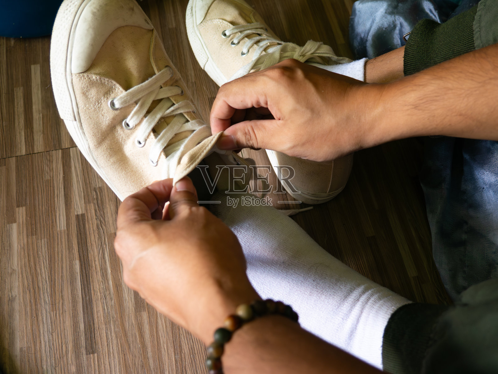 居家木地板上，穿着米白色帆布鞋和白袜的人的俯视图照片摄影图片