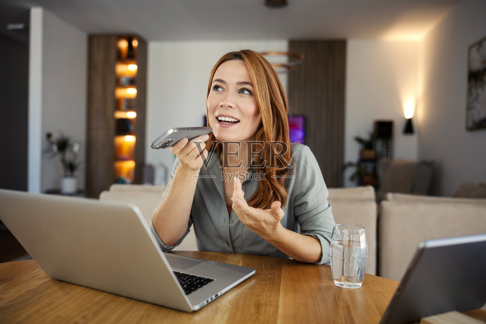 在家工作的女性正在用手机发送语音消息照片摄影图片