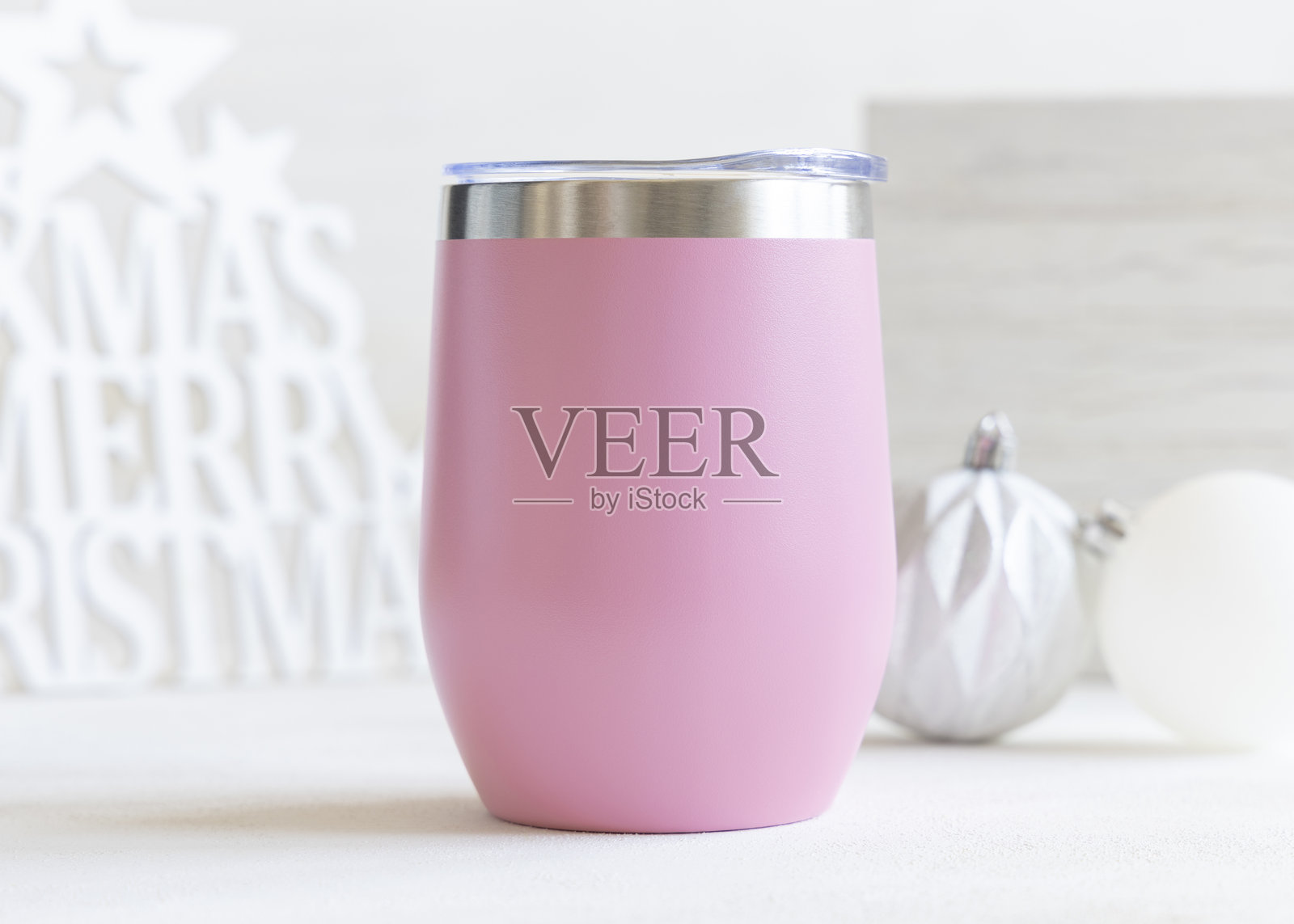 粉色空白不锈钢酒杯，靠近桌上的圣诞装饰球，特写，样机照片摄影图片