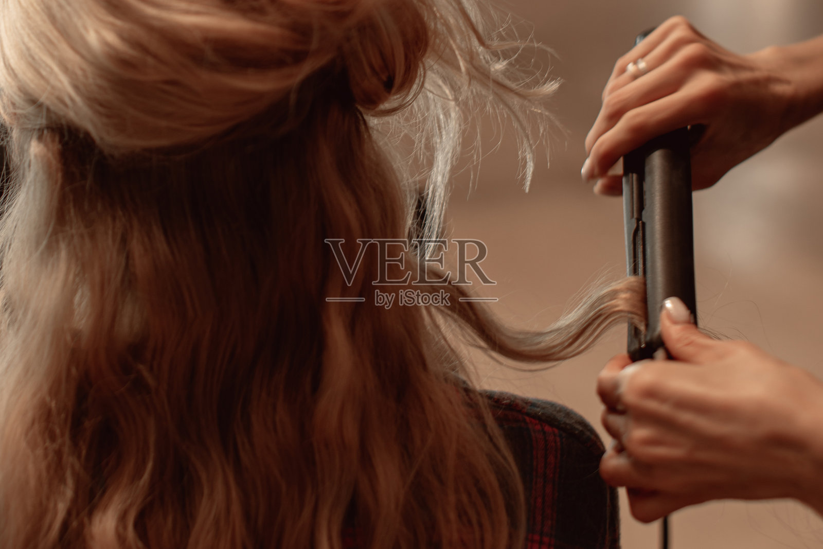 发型师的女性双手使用专业热造型器为长金发做发型照片摄影图片
