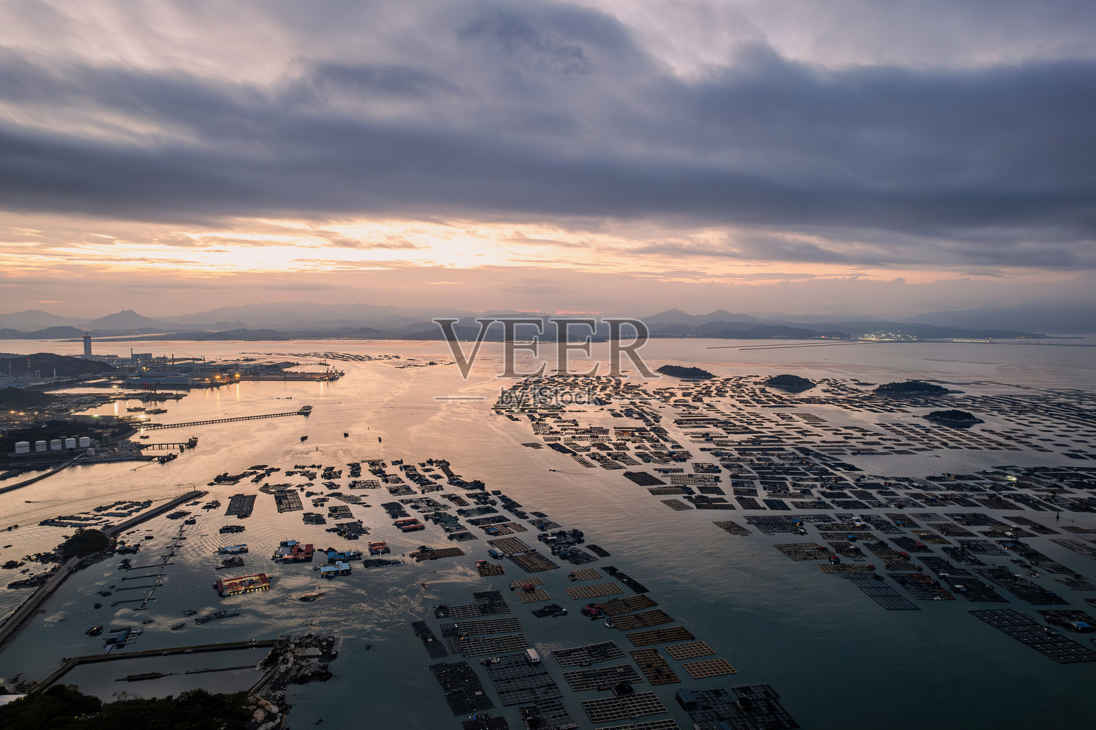 夕阳的余晖照耀着近海的养殖场。照片摄影图片