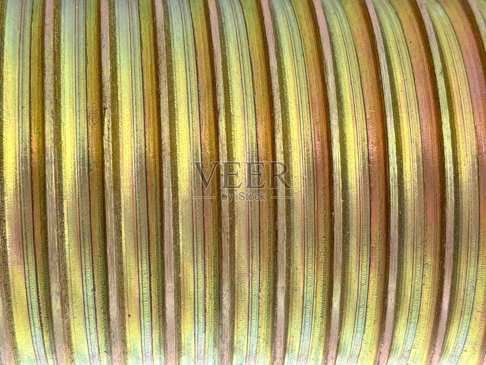 金色金属线材特写，表面有精细的凹槽和光线反射，非常适合工业、机械或抽象纹理设计。照片摄影图片