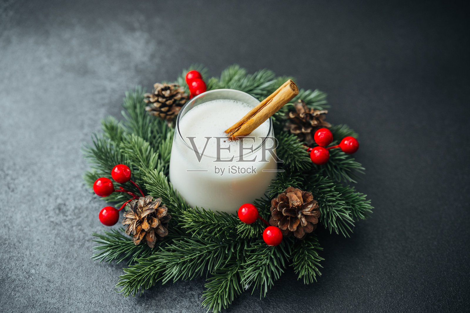 奶油质感的冬季饮品，配有肉桂棒、松针、浆果和松果。照片摄影图片