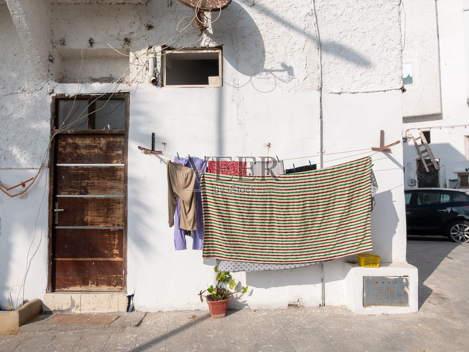 摩洛哥拉巴特阳光明媚的社区里，白色建筑外晾晒的衣物照片摄影图片
