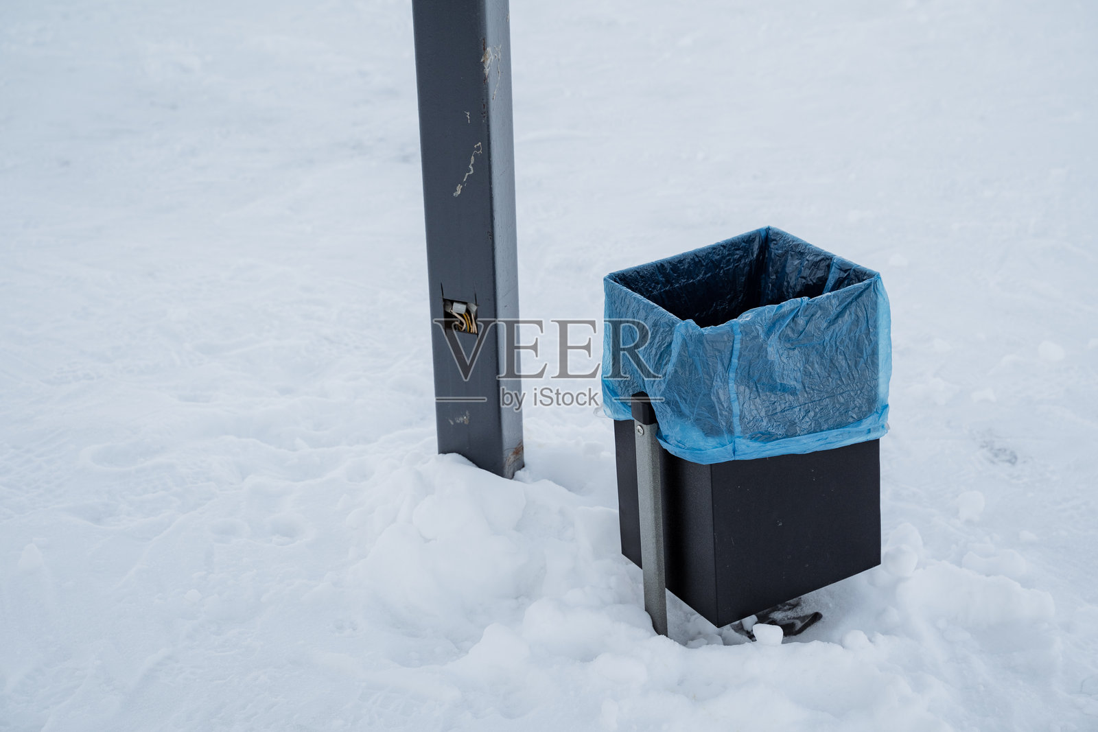 在风景如画的冬季景观中，一个垃圾桶被厚厚的积雪完全覆盖，突出了垃圾与宁静环境之间的对比。照片摄影图片