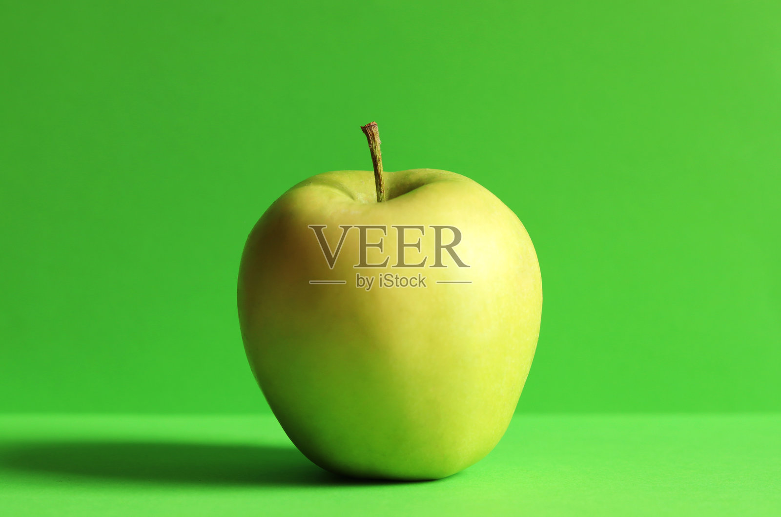 一个绿色的苹果，孤立在绿色背景上照片摄影图片
