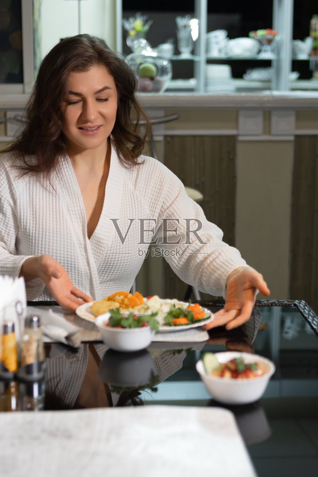 身穿白色病号服的女性患者在医疗机构餐厅吃早餐。照片摄影图片
