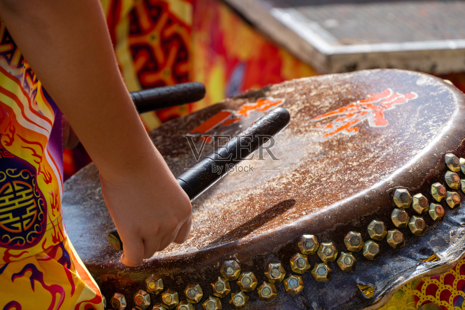 特写：一位身着色彩斑斓服饰、装饰细节丰富的表演者正在敲击传统鼓照片摄影图片