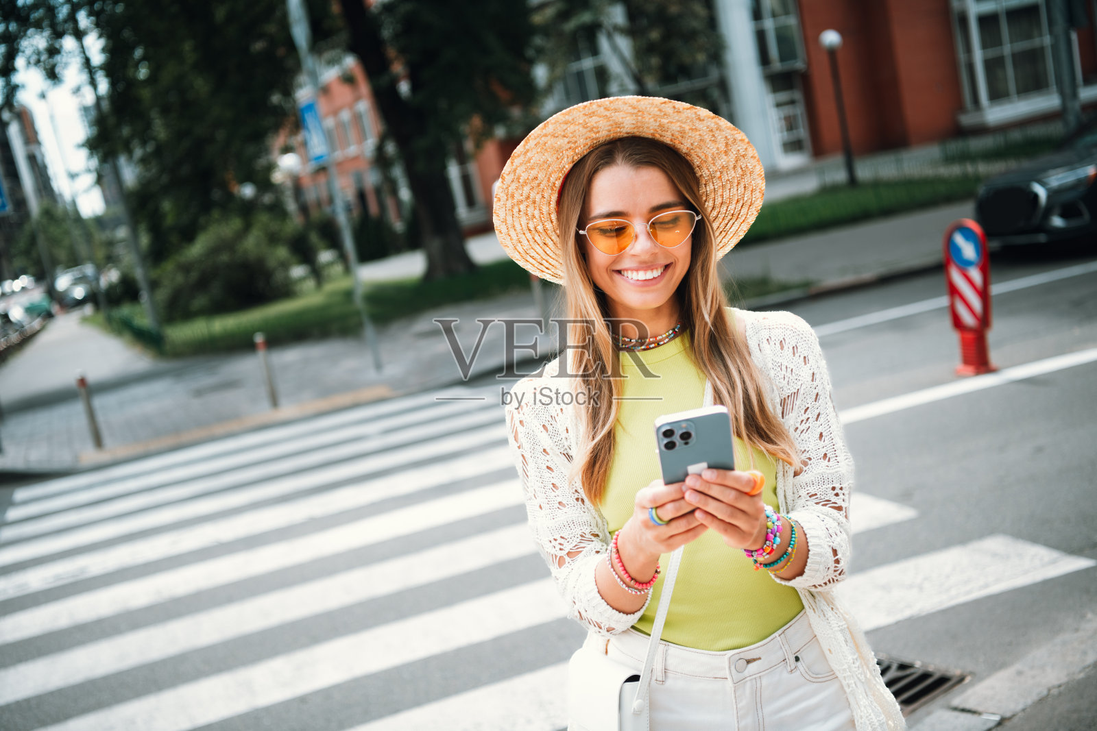 年轻女孩戴着太阳帽，在夏日阳光明媚的城市街道上漫步，享受时尚休闲的户外生活方式。照片摄影图片