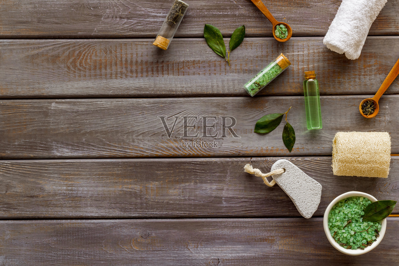 俯视视角，木质背景上，研钵和研杵中放有茶树精油和海盐，旁边有绿叶。照片摄影图片