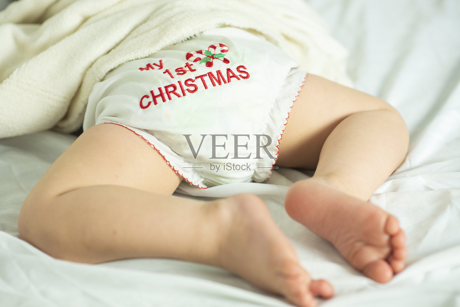 身穿写有“我的第一个圣诞节”字样的白色内裤的婴儿正在睡觉，特写文字。照片摄影图片