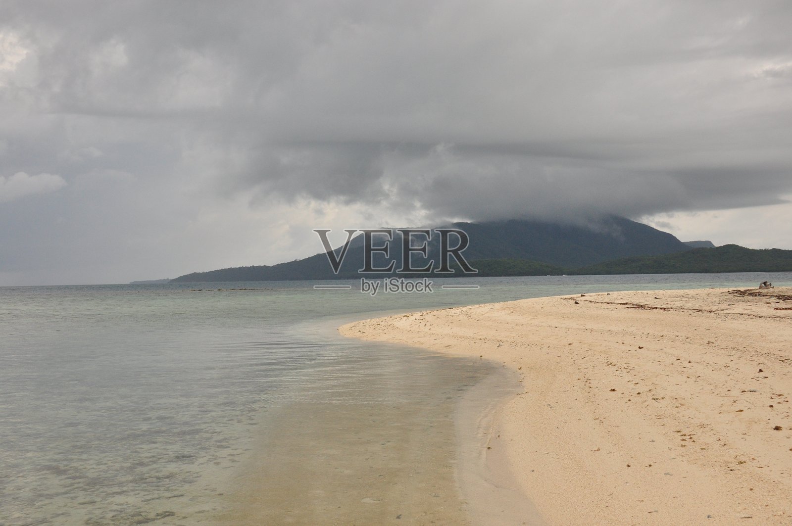 宁静日子里，多云的沙滩景色，有沙质海岸和远处的山峦照片摄影图片
