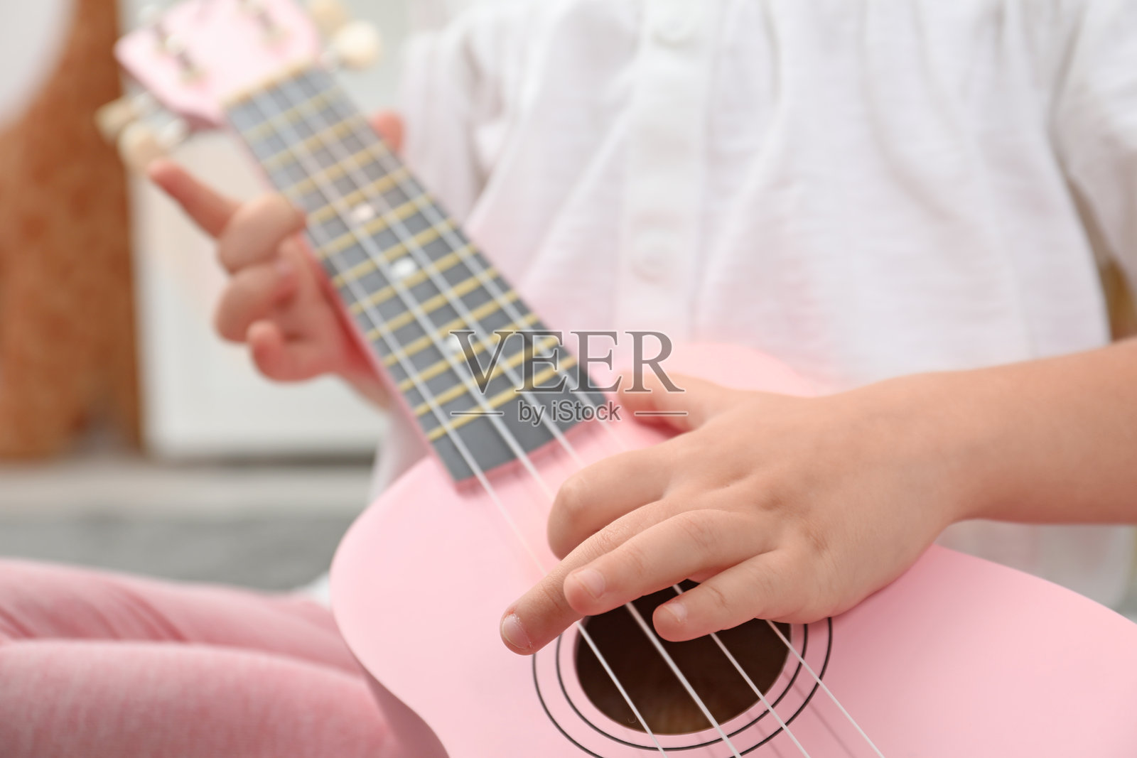 一个可爱的小女孩在家弹奏尤克里里，特写镜头照片摄影图片